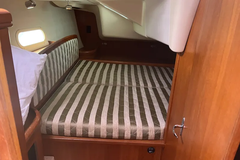 Slide: The Image of Cozy cabin interior of 2004 Hunter 36 sailboat with striped bedding and wooden finish. - 11