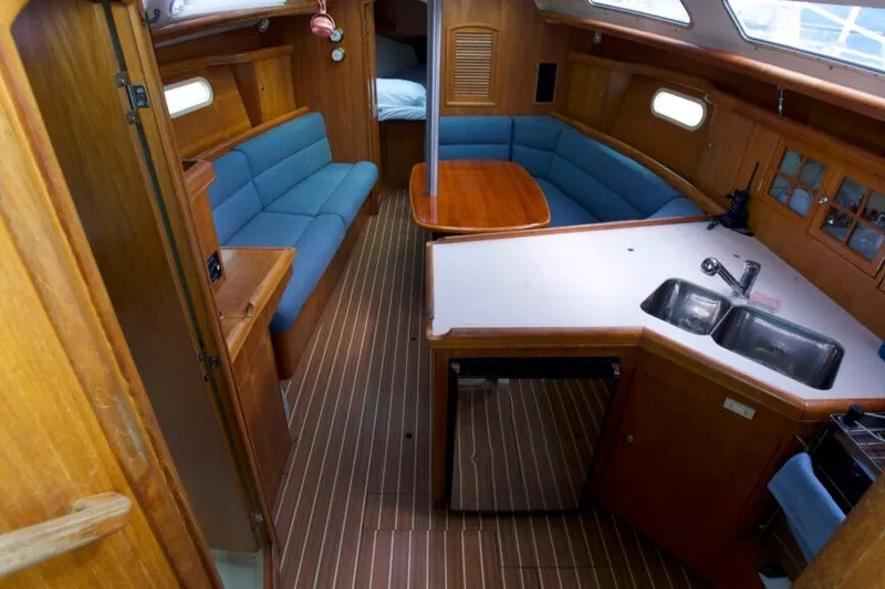 Slide: The Image of Interior of 2004 Hunter 36 sailboat with wood finish, blue seating, and kitchenette. - 7