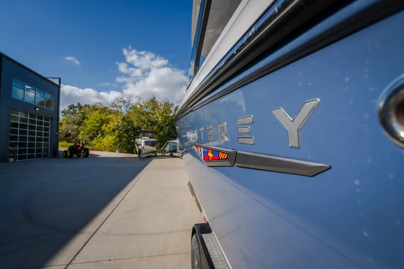 Slide: The Image of 2027 Monterey Elite 27 OB boat parked outdoors near a modern building. - 56