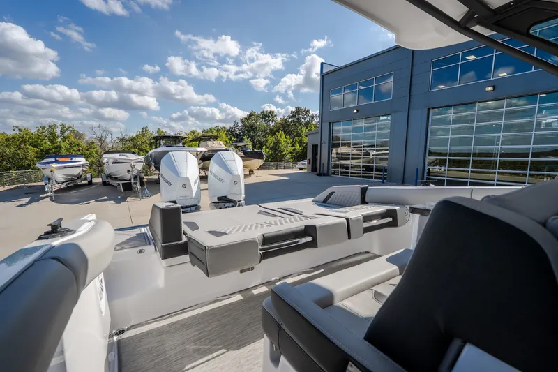 Slide: The Image of 2027 Monterey Elite 27 OB boat at a marina with other boats and modern building. - 37