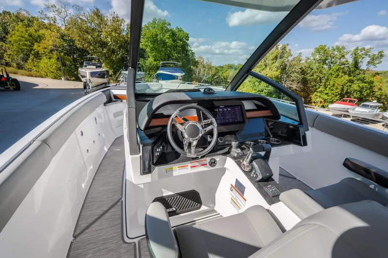 Slide: The Image of 2027 Monterey Elite 27 OB boat cockpit with modern steering and dashboard, surrounded by lush greenery. - 24
