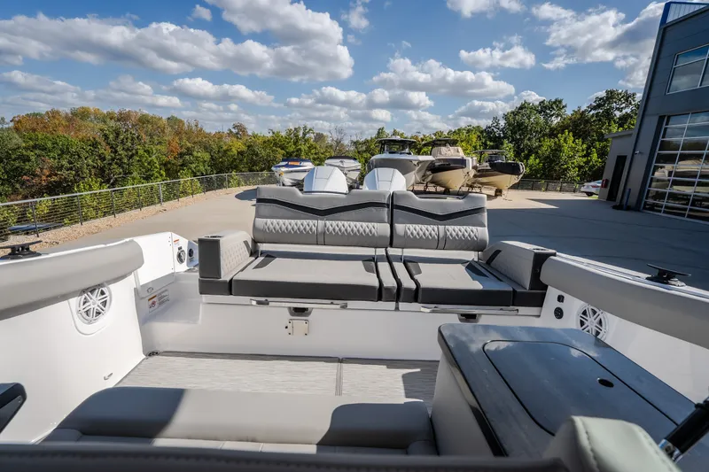 Slide: The Image of 2027 Monterey Elite 27 OB boat interior with plush seating, docked under a blue sky. - 23