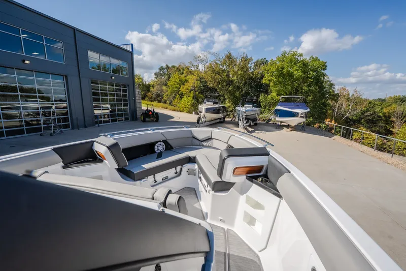 Slide: The Image of 2027 Monterey Elite 27 OB boat with sleek interior, parked near modern building and trees. - 40
