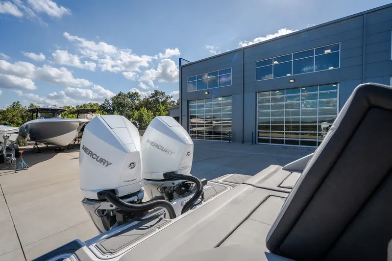 Slide: The Image of 2027 Monterey Elite 27 OB boat with dual Mercury engines outside a modern facility. - 34