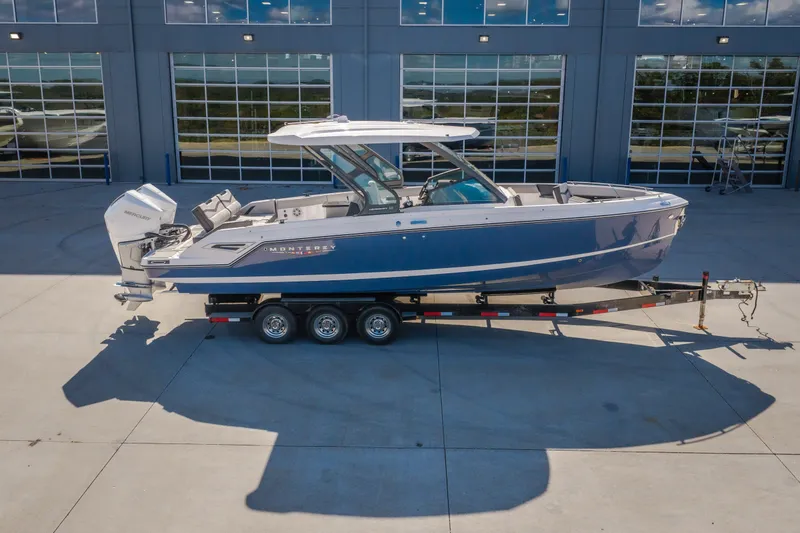 Slide: The Image of 2027 Monterey Elite 27 OB boat on trailer, parked outside a modern building. - 70