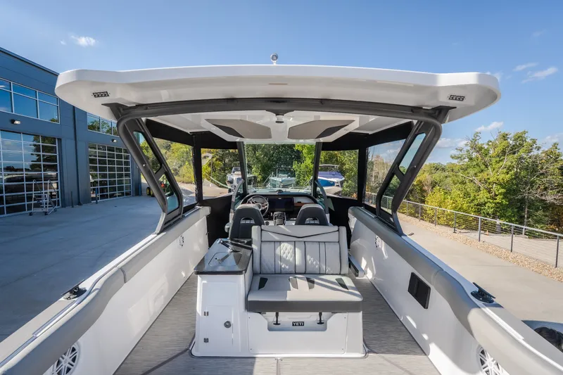Slide: The Image of 2027 Monterey Elite 27 OB boat interior with seating and helm, parked outdoors. - 64