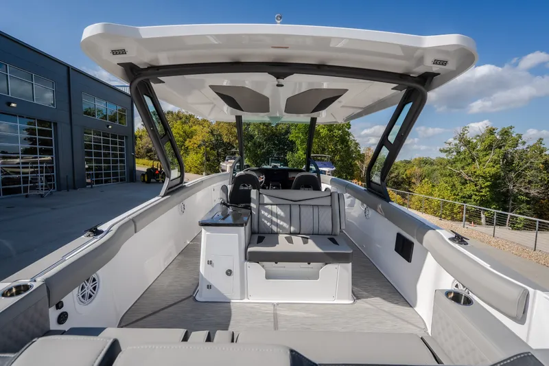 Slide: The Image of 2027 Monterey Elite 27 OB boat interior with seating and canopy, parked outdoors. - 16