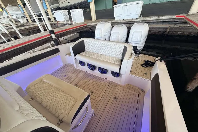 Slide: The Image of 2014 Nor-Tech 340 Sport boat interior with cushioned seating and triple outboard motors. - 5