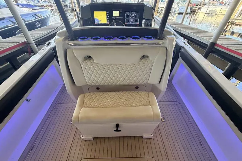 Slide: The Image of 2014 Nor-Tech 340 Sport boat interior with white quilted seating and illuminated console. - 7