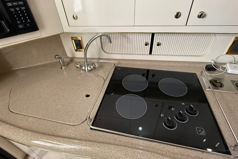 Slide: The Image of 1997 Sea Ray Sundancer 400 kitchen with stovetop, sink, and storage cabinets. - 33