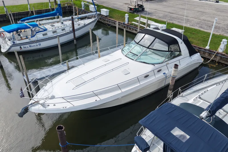 The Image of 1997 Sea Ray Sundancer 400 yacht docked in marina, featuring sleek white design and black canopy. - 0