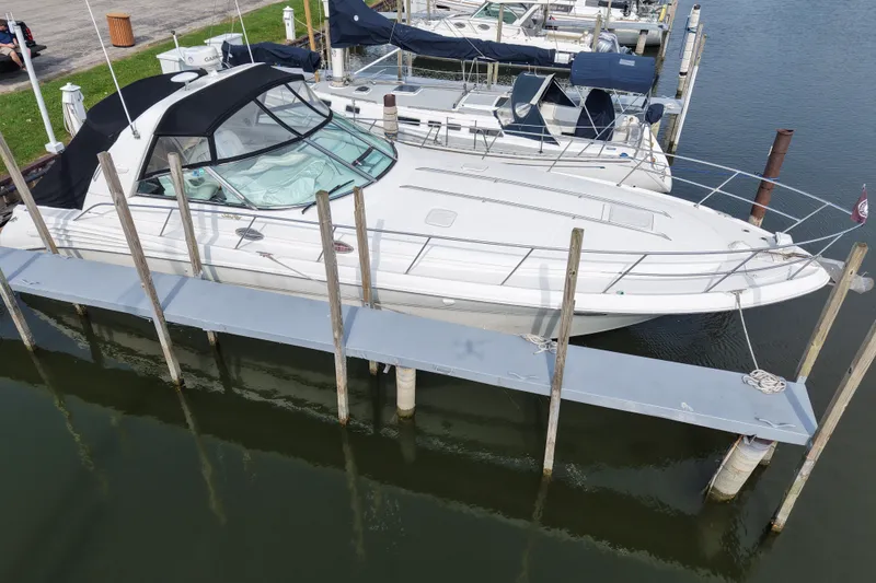 Slide: The Image of 1997 Sea Ray Sundancer 400 docked at marina, featuring sleek white design and black canopy. - 1