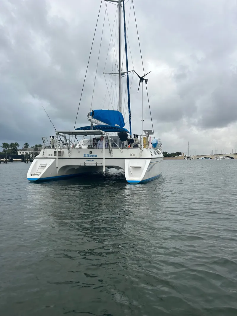 Slide: The Image of A 1990 Jeantot Privilege 39 catamaran on calm water under a cloudy sky. - 3