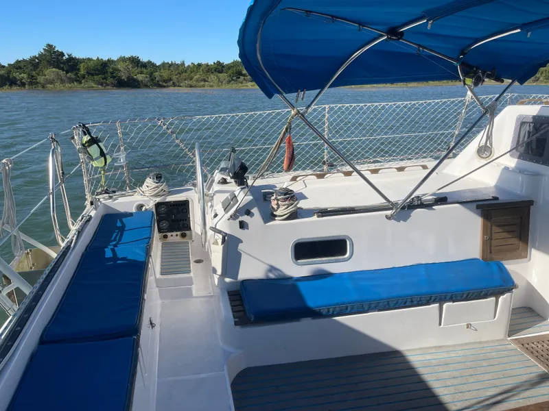 Slide: The Image of The image shows the deck of a 1990 Jeantot Privilege 39 with blue cushions and a blue sunshade. - 27