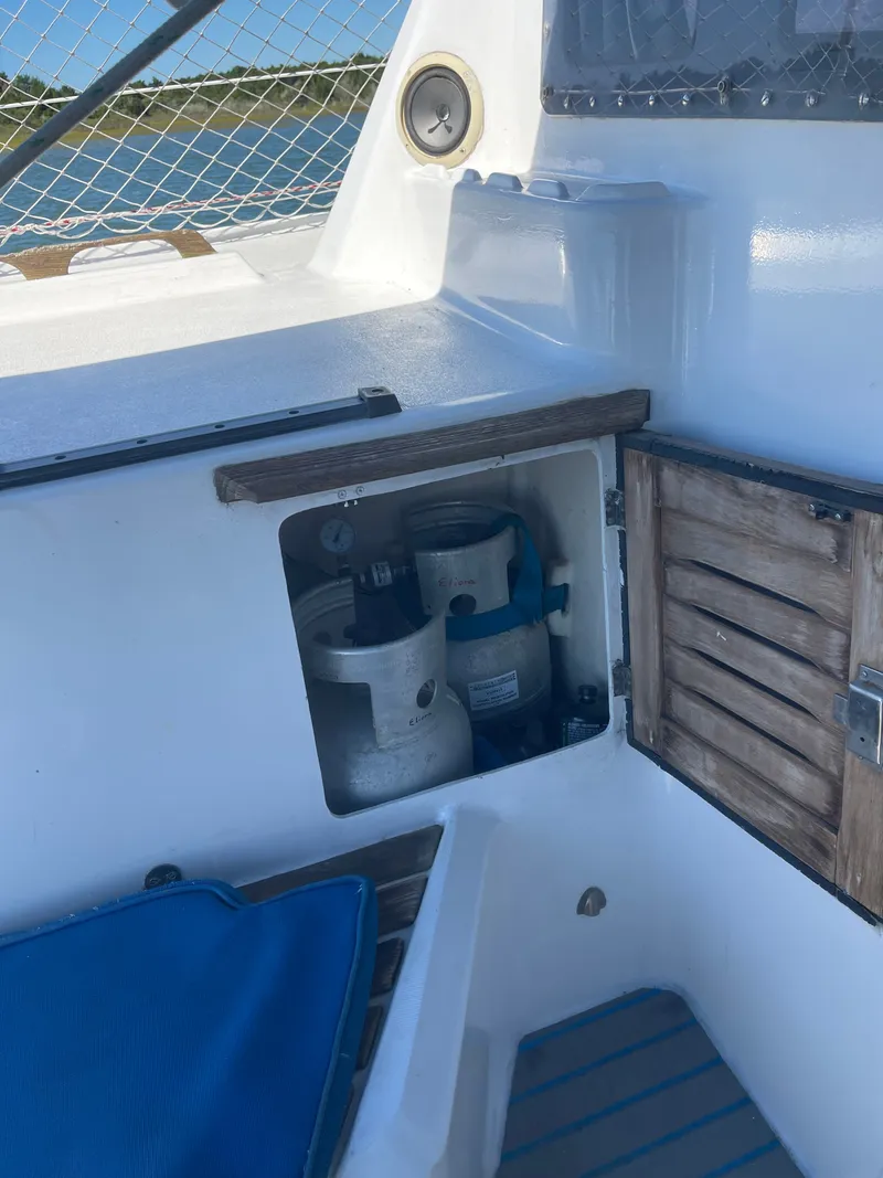 Slide: The Image of A storage area on a 1990 Jeantot Privilege 39 with two gas cylinders and wooden doors. - 10