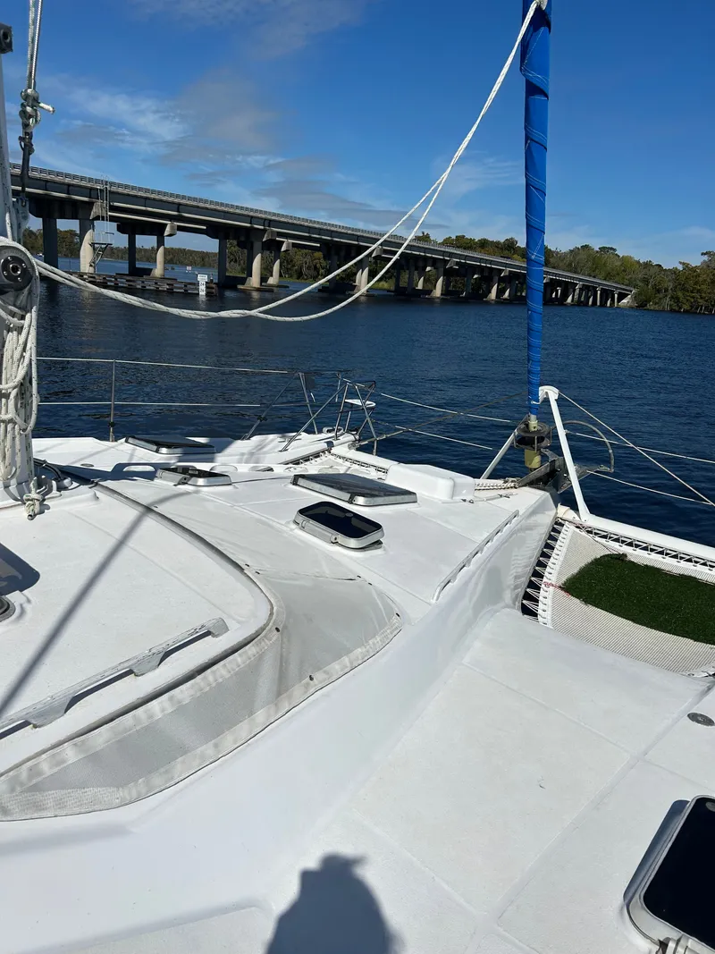 Slide: The Image of A 1990 Jeantot Privilege 39 catamaran on a calm river with a bridge in the background. - 15