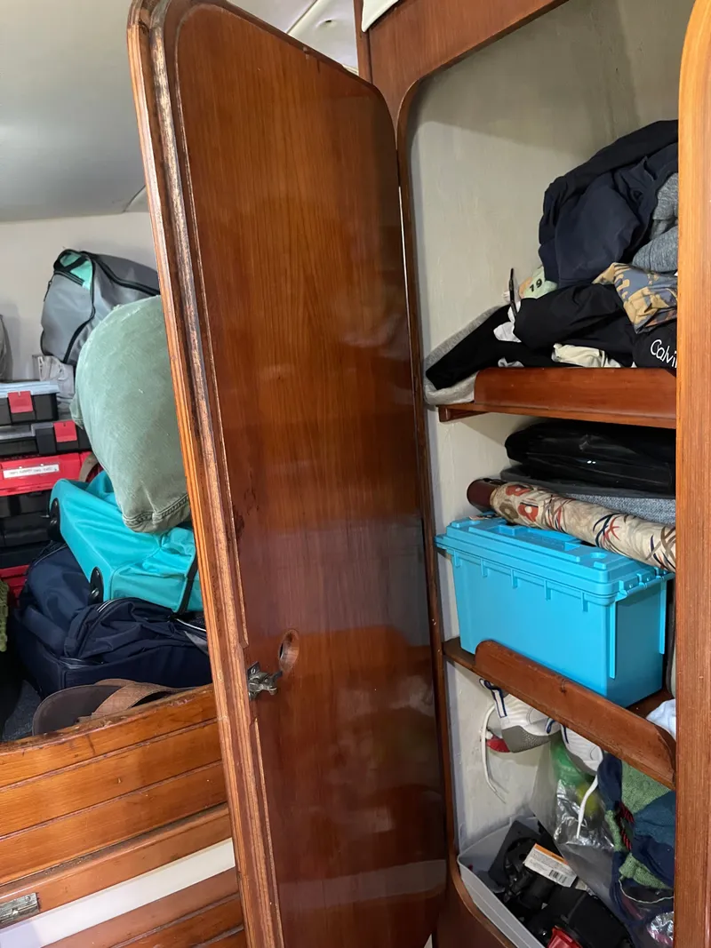 Slide: The Image of A wooden door cabinet filled with clothes and boxes inside a boat. - 40