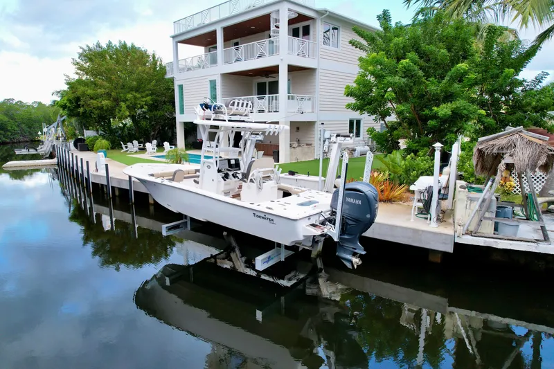 Slide: The Image of 2021 Tidewater 2500 Carolina Bay boat docked by a waterfront house. - 1