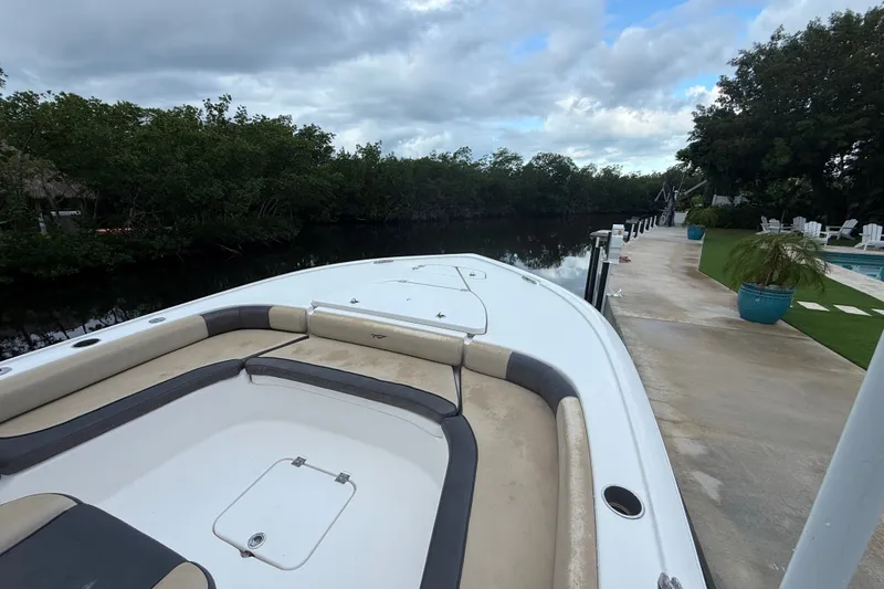 Slide: The Image of 2021 Tidewater 2500 Carolina Bay boat docked by a serene riverside with lush greenery. - 14