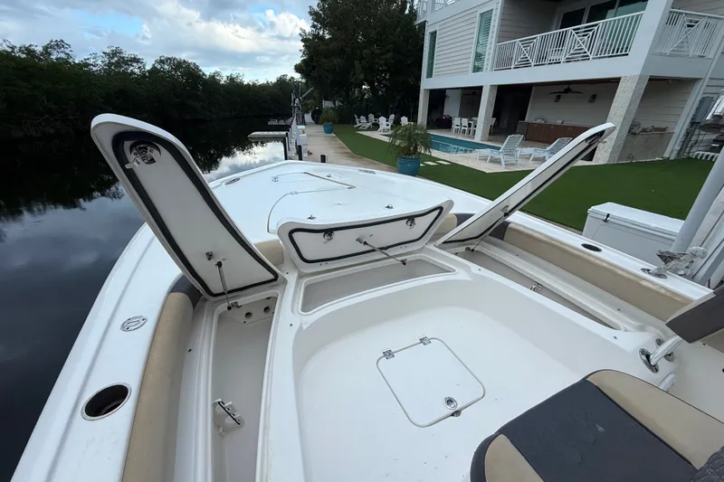 Slide: The Image of 2021 Tidewater 2500 Carolina Bay boat with open storage compartments, docked near a modern house. - 16