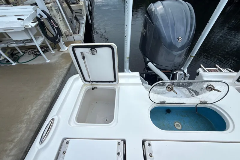 Slide: The Image of 2021 Tidewater 2500 Carolina Bay boat with open storage compartments and outboard motor. - 10