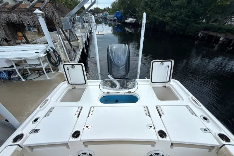 Slide: The Image of 2021 Tidewater 2500 Carolina Bay boat with open storage compartments, docked by a canal. - 8
