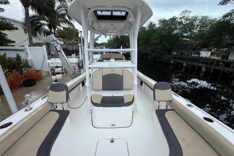 Slide: The Image of 2021 Tidewater 2500 Carolina Bay boat interior with seating, docked near lush greenery. - 21