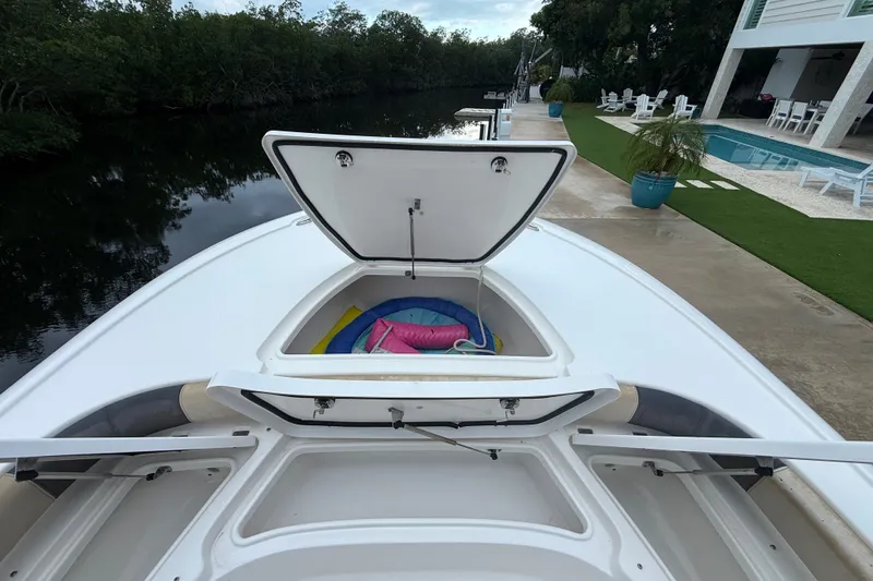 Slide: The Image of 2021 Tidewater 2500 Carolina Bay boat with open storage compartments by a riverside dock. - 19