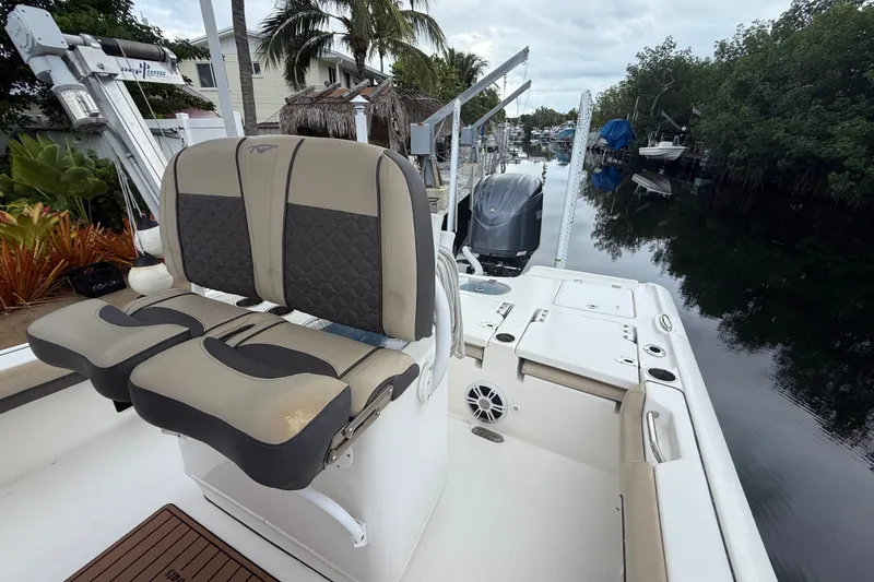 Slide: The Image of 2021 Tidewater 2500 Carolina Bay boat with dual seats, docked near lush greenery. - 24