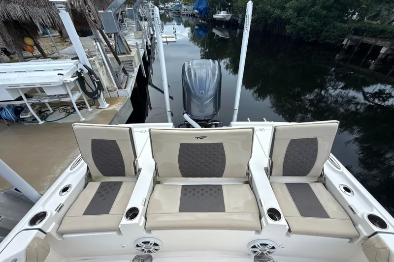 Slide: The Image of 2021 Tidewater 2500 Carolina Bay boat with cushioned seating and outboard motor in a marina. - 7