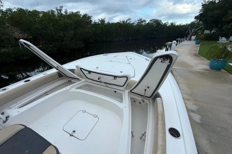 Slide: The Image of 2021 Tidewater 2500 Carolina Bay boat with open storage compartments docked by a canal. - 17