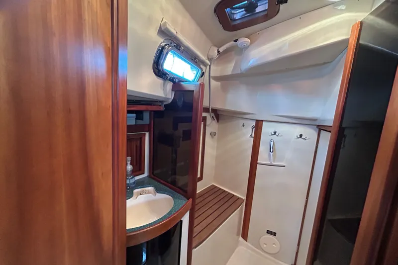 Slide: The Image of Interior of 2001 Sabre 402 sailboat bathroom with sink, wooden accents, and porthole window. - 20