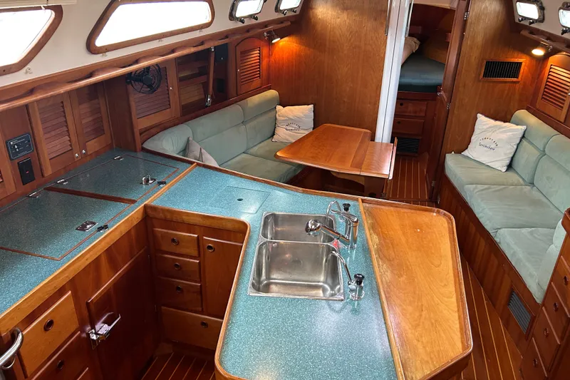 Slide: The Image of Interior of 2001 Sabre 402 sailboat with wood finish, cozy seating, and compact kitchen area. - 15