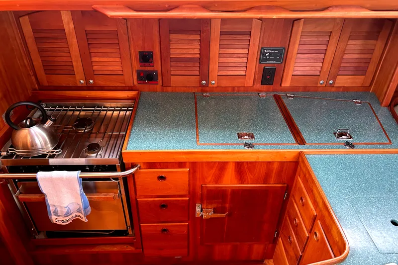 Slide: The Image of 2001 Sabre 402 yacht kitchen with wooden cabinetry, stove, and teal countertops. - 12