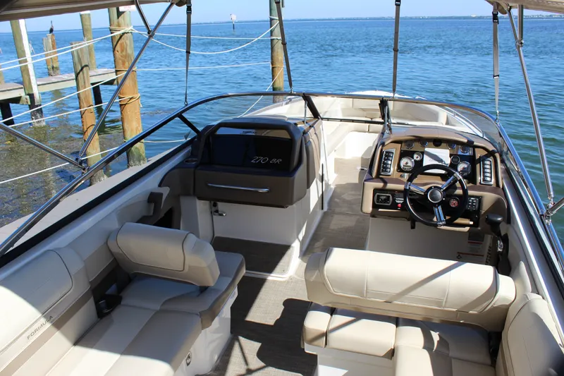 Slide: The Image of 2015 Formula 270 Bowrider boat interior with steering wheel and seating, docked by the water. - 26