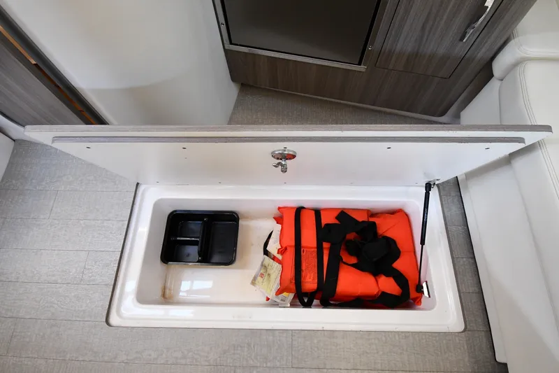 Slide: The Image of Storage compartment in 2021 Regal 35 Sport Coupe with life jacket and tray. - 48