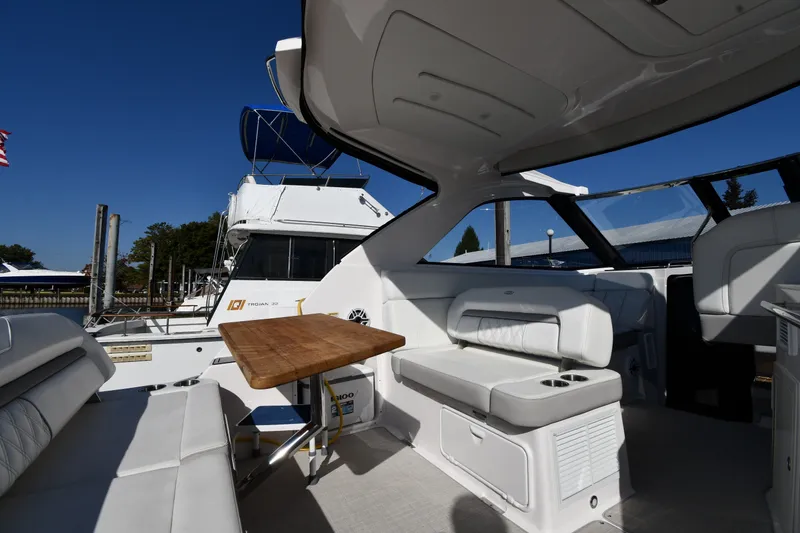 Slide: The Image of 2021 Regal 35 Sport Coupe interior with seating and wooden table, docked under clear blue sky. - 17