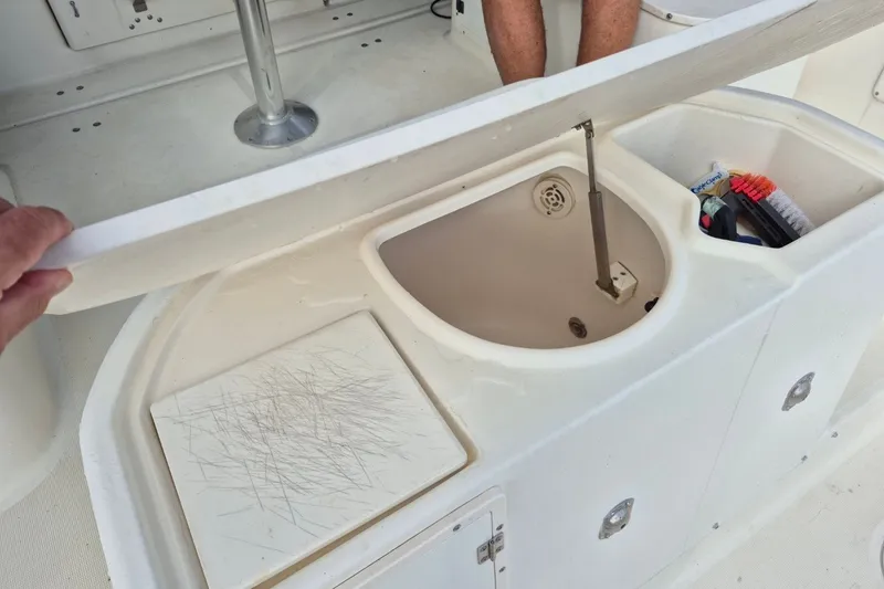 Slide: The Image of 1996 Pursuit 3000 Offshore boat storage compartment with cleaning supplies and cutting board. - 18