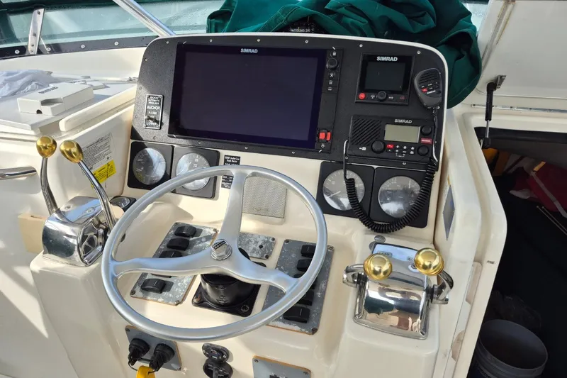 Slide: The Image of Control panel of a 1996 Pursuit 3000 Offshore boat with steering wheel and navigation equipment. - 21