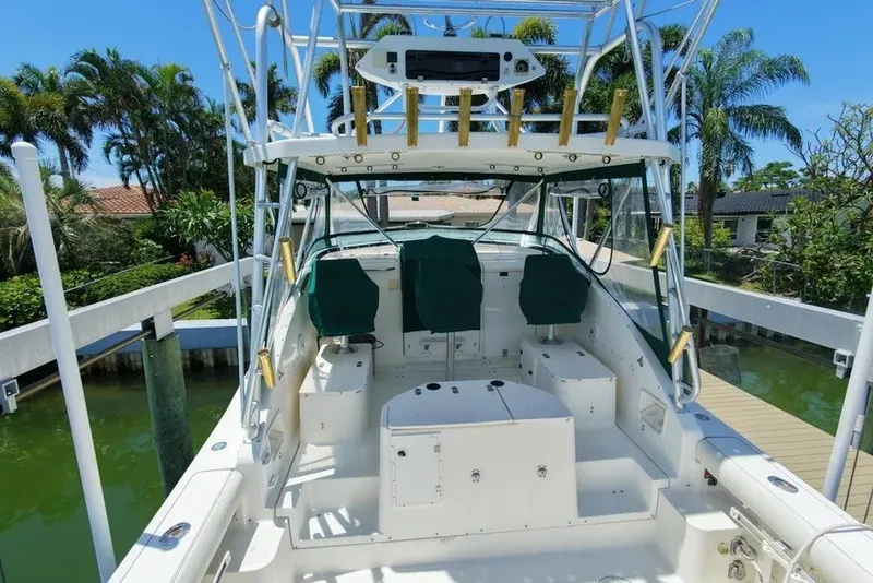 Slide: The Image of 1996 Pursuit 3000 Offshore boat with green seats, docked near lush greenery. - 9