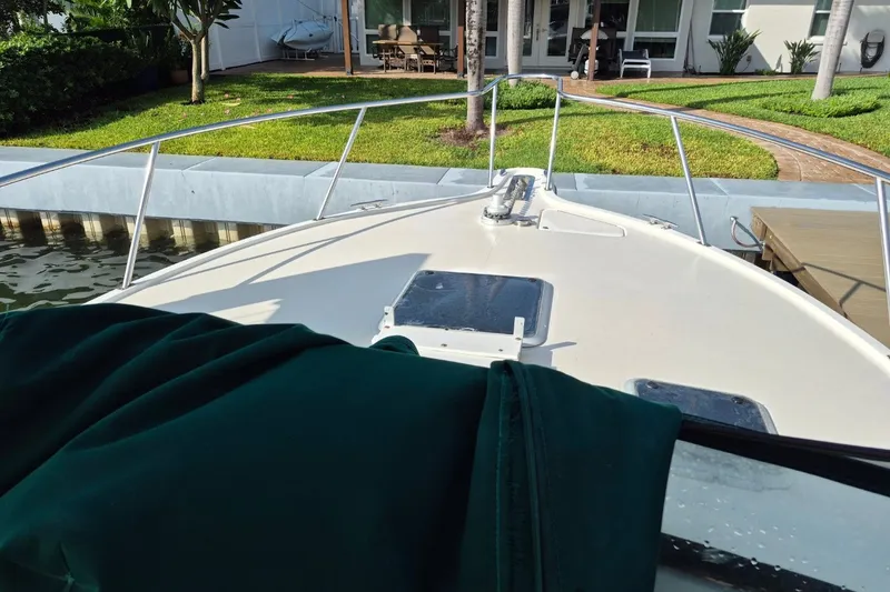 Slide: The Image of Bow view of a 1996 Pursuit 3000 Offshore boat docked near a waterfront home. - 54