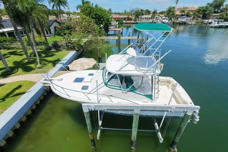 Slide: The Image of 1996 Pursuit 3000 Offshore boat docked on a lift in a scenic canal. - 1