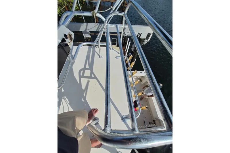 Slide: The Image of 1996 Pursuit 3000 Offshore boat deck with metal railings and fishing rod holders. - 62
