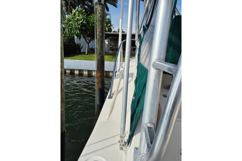 Slide: The Image of 1996 Pursuit 3000 Offshore boat docked near lush greenery and waterfront home. - 64