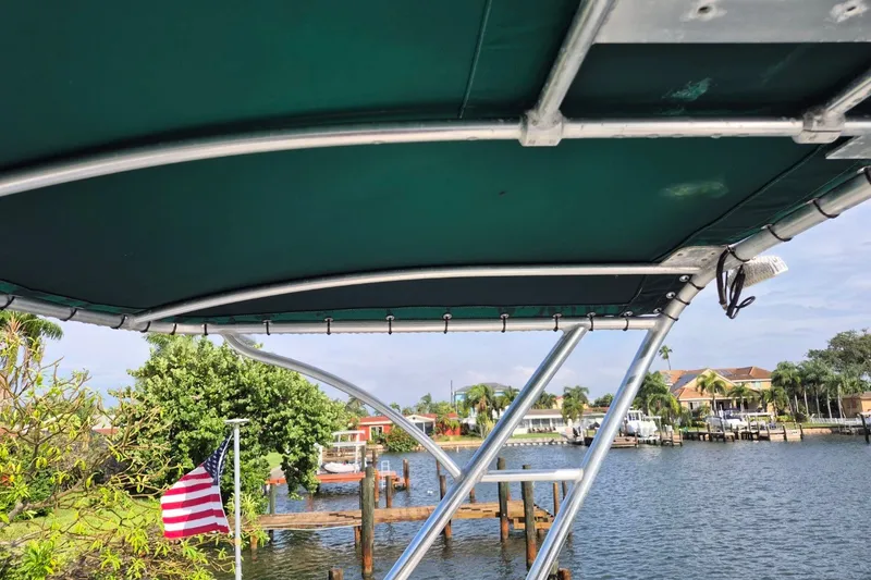Slide: The Image of 1996 Pursuit 3000 Offshore boat with green canopy, docked near waterfront homes. - 59