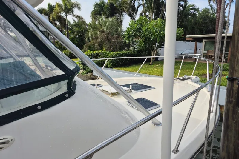 Slide: The Image of 1996 Pursuit 3000 Offshore boat docked near lush greenery and a house. - 11