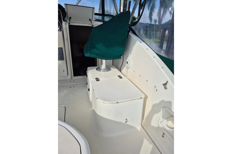 Slide: The Image of 1996 Pursuit 3000 Offshore boat interior with green cover and storage compartment. - 20