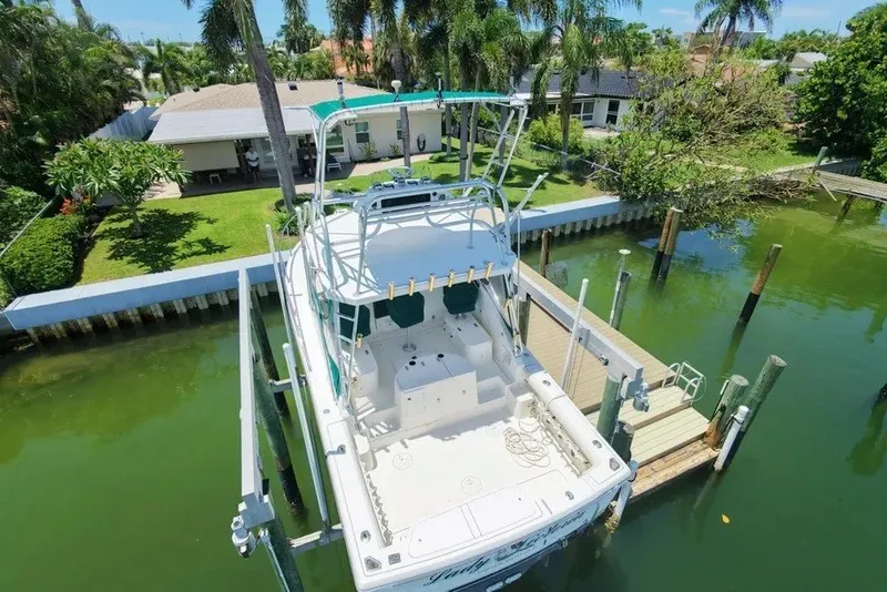 Slide: The Image of 1996 Pursuit 3000 Offshore boat docked in a scenic residential canal setting. - 7