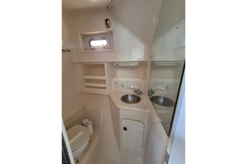Slide: The Image of 1996 Pursuit 3000 Offshore boat bathroom with sink, toilet, and storage shelves. - 43