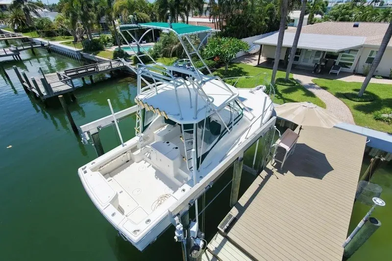 Slide: The Image of 1996 Pursuit 3000 Offshore boat docked at a waterfront property with lush greenery. - 5